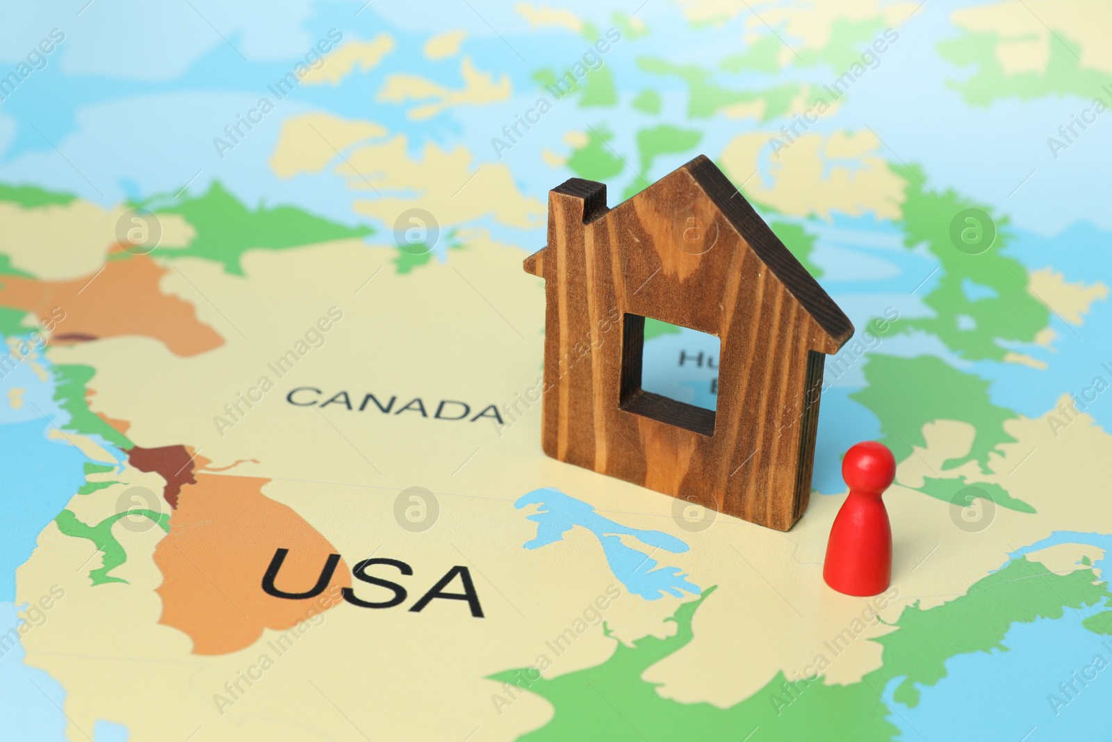 Photo of Wooden house model and red human figure on world map. Accommodation search