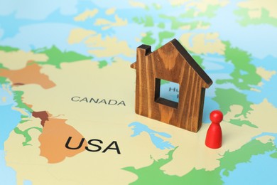 Photo of Wooden house model and red human figure on world map. Accommodation search