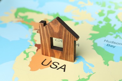 Photo of Wooden house model on world map, closeup. Accommodation search