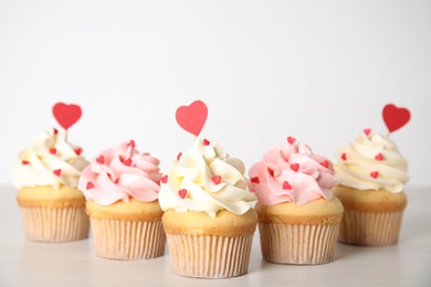 Photo of Tasty sweet cupcakes on white table. Happy Valentine's Day