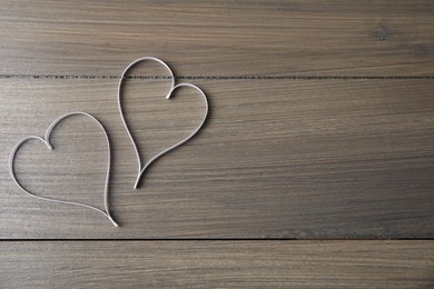 Photo of Hearts made of white ribbon on wooden background, flat lay with space for text. Valentine's day celebration