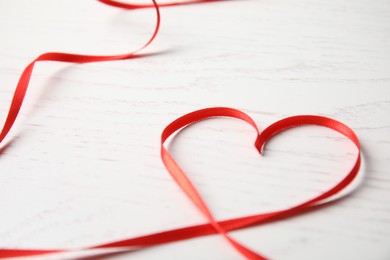 Photo of Heart made of red ribbon on white wooden background. Valentine's day celebration