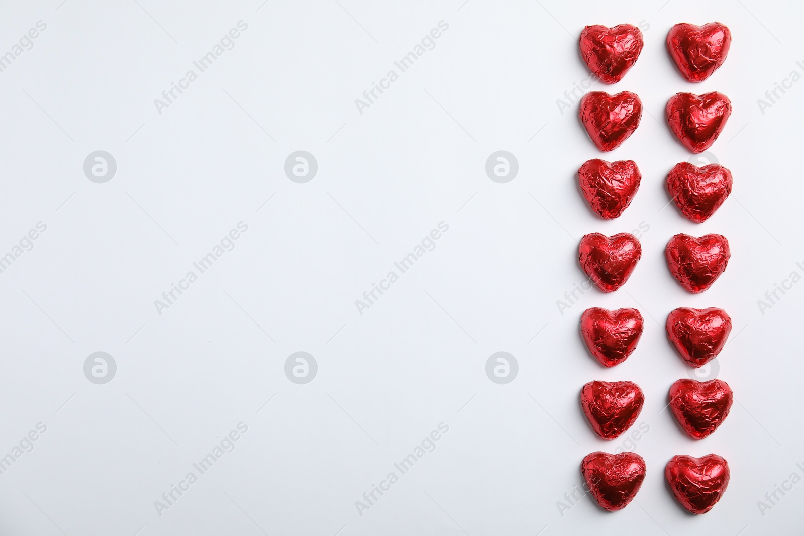 Photo of Heart shaped chocolate candies on white background, flat lay with space for text. Valentine's day treat