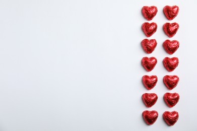 Photo of Heart shaped chocolate candies on white background, flat lay with space for text. Valentine's day treat