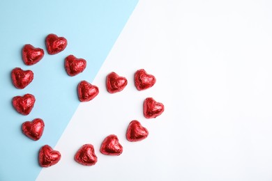 Photo of Heart of chocolate candies on color background, flat lay with space for text. Valentine's day treat