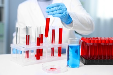 Photo of Laboratory testing. Doctor taking test tube with blood sample from rack indoors, closeup