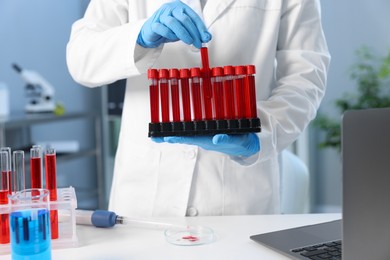 Photo of Laboratory testing. Doctor with blood samples in tubes indoors, closeup