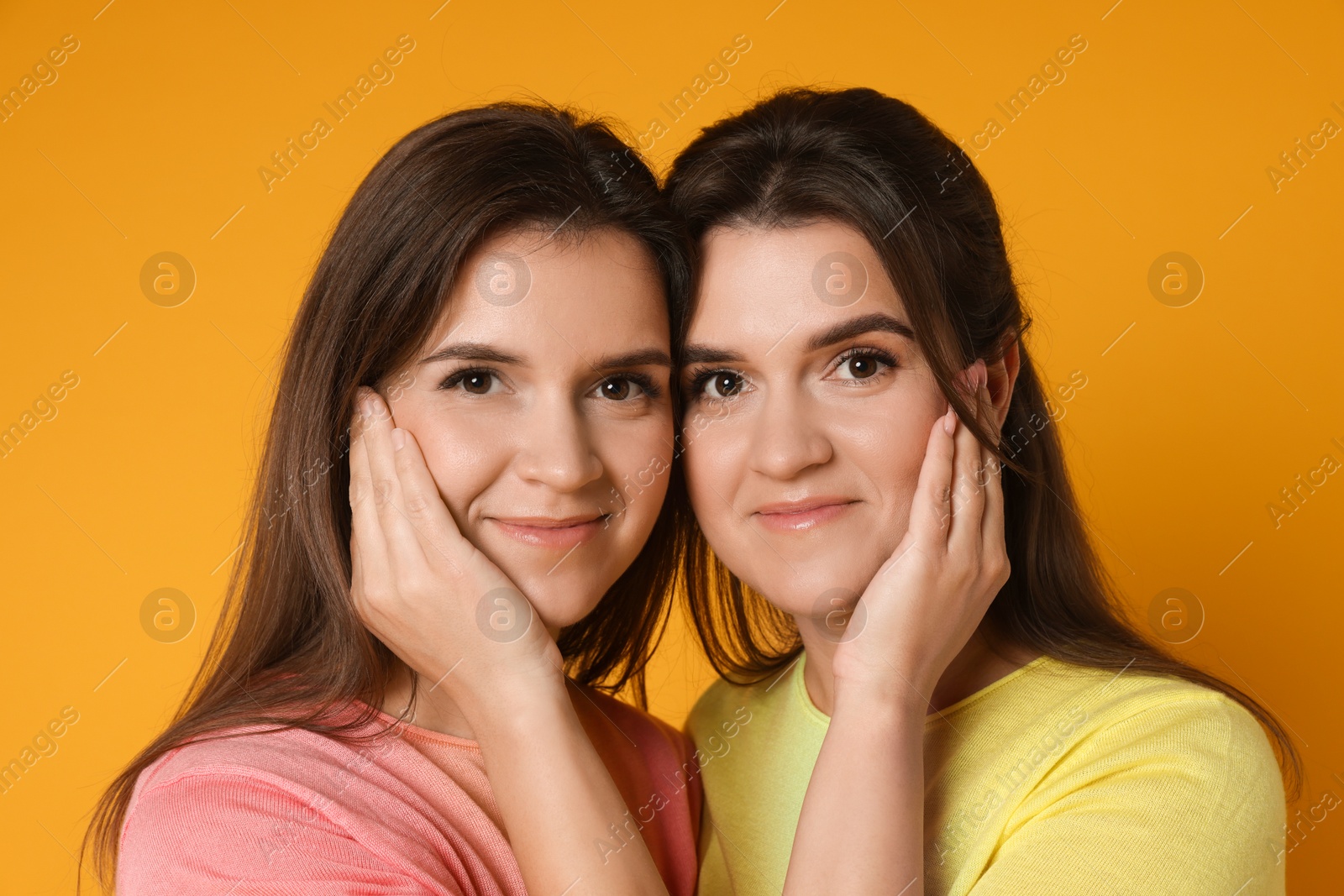 Photo of Portrait of happy twin sisters on orange background