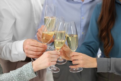 Photo of Happy coworkers clinking glasses of wine during office Christmas party, closeup