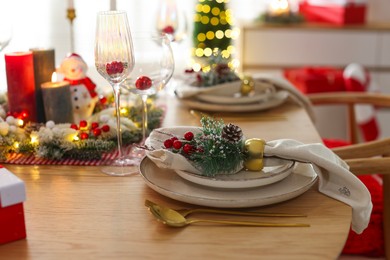 Photo of Christmas celebration. Festive table setting with dishware, glasses and decor in room