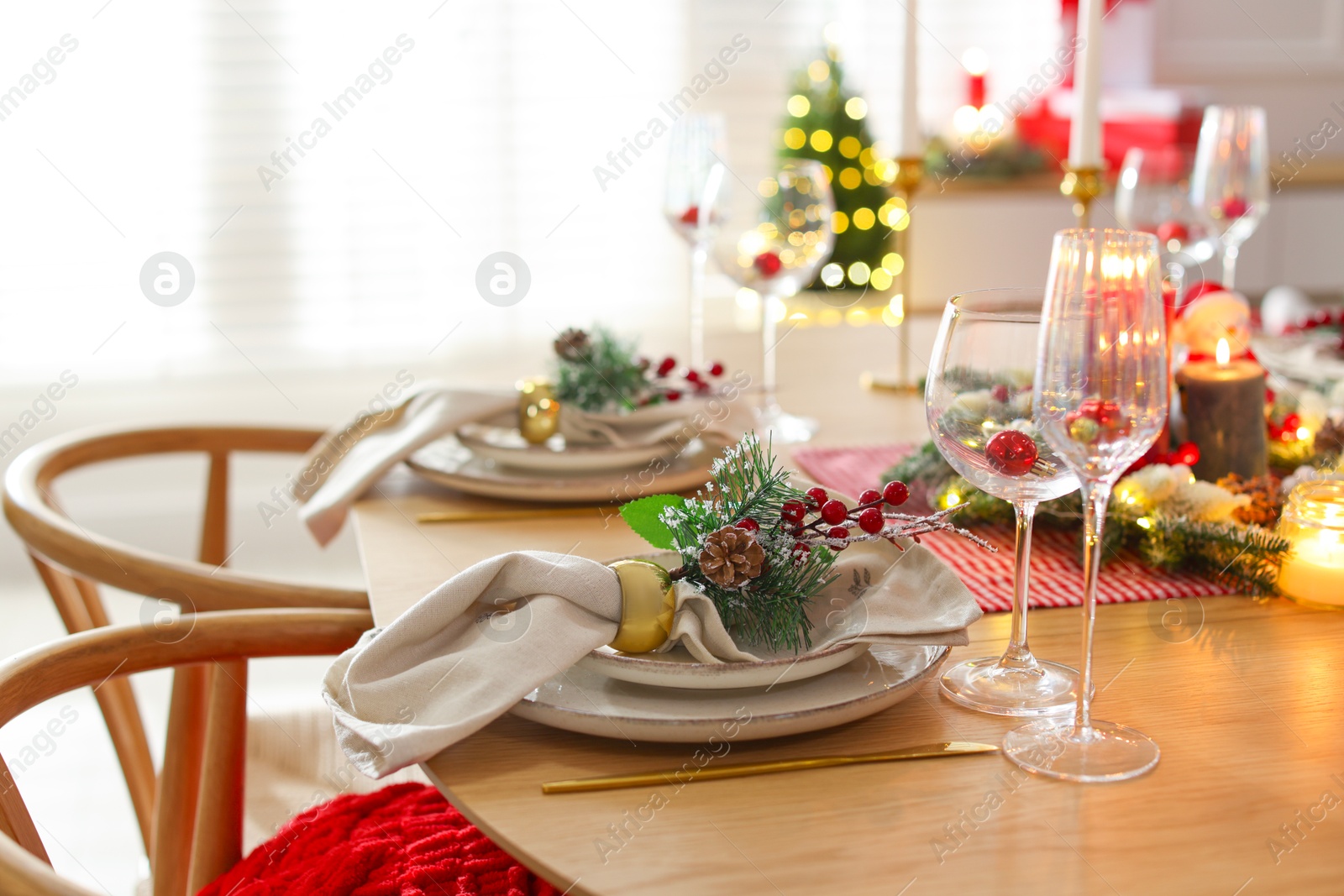 Photo of Christmas celebration. Festive table setting with dishware, glasses and decor in room