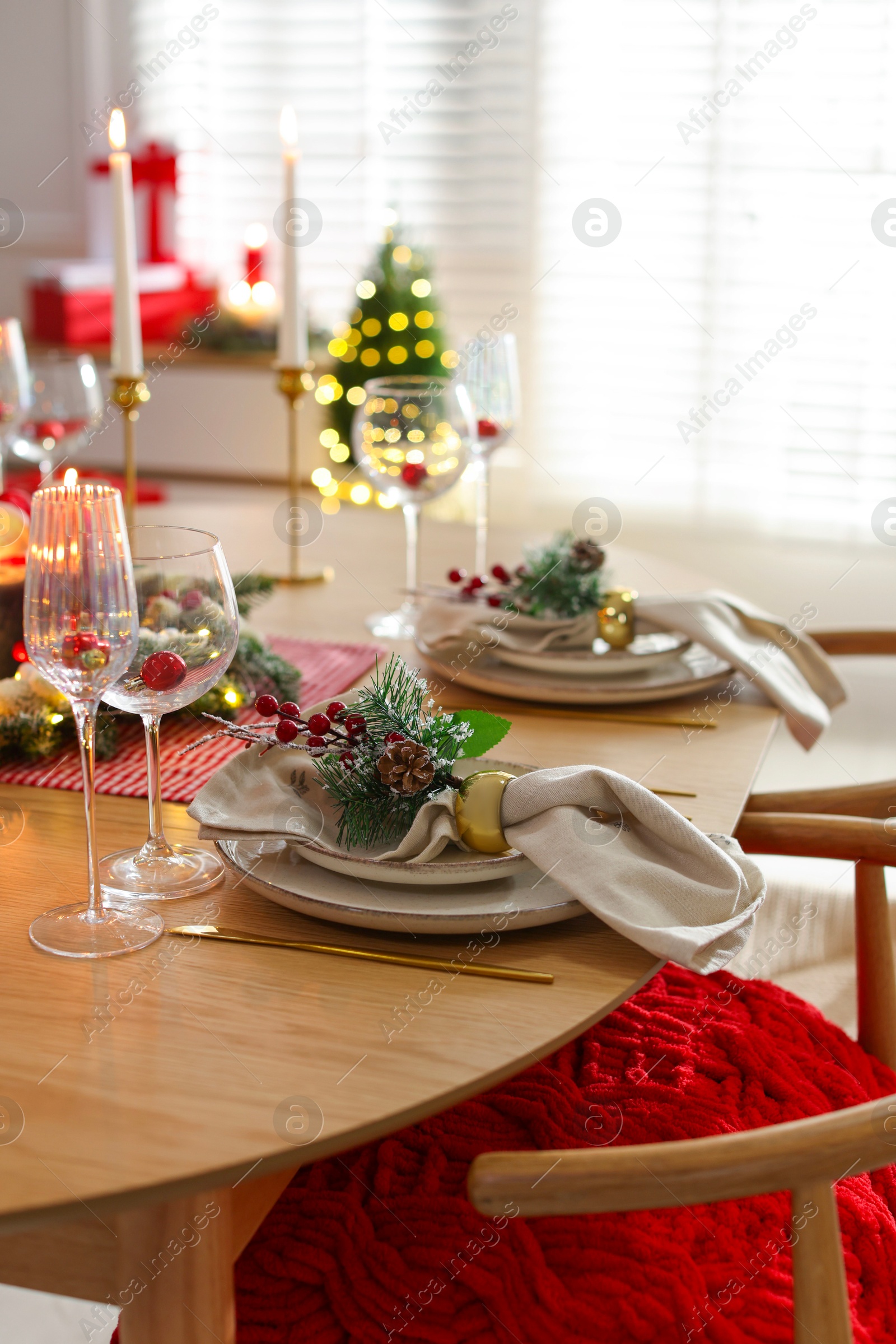 Photo of Christmas celebration. Festive table setting with dishware, glasses and decor in room