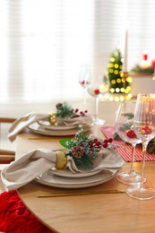 Photo of Christmas celebration. Festive table setting with dishware, glasses and decor in room