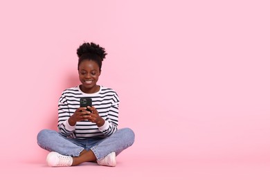 Photo of Happy woman with smartphone on pink background. Space for text