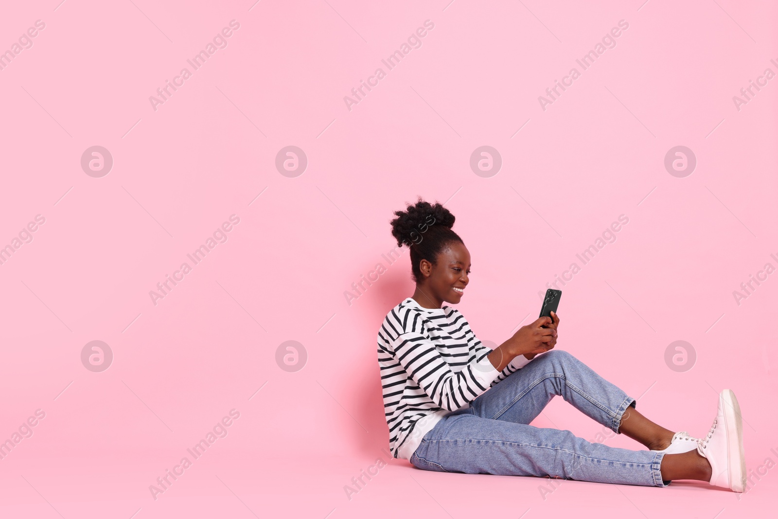 Photo of Happy woman with smartphone on pink background. Space for text