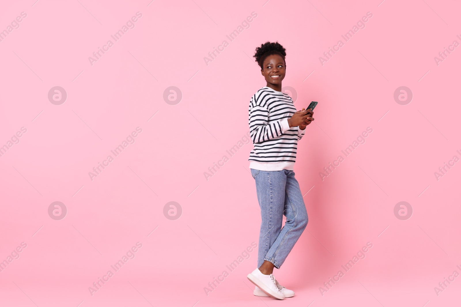 Photo of Happy woman with smartphone on pink background. Space for text