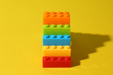 Photo of Construction toy. Figure made with building bricks on yellow background