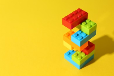 Photo of Construction toy. Figure made with building bricks on yellow background, space for text