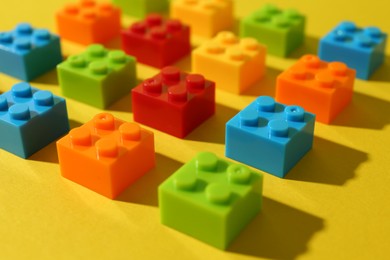 Photo of Construction toy. Colorful building bricks on yellow background, closeup