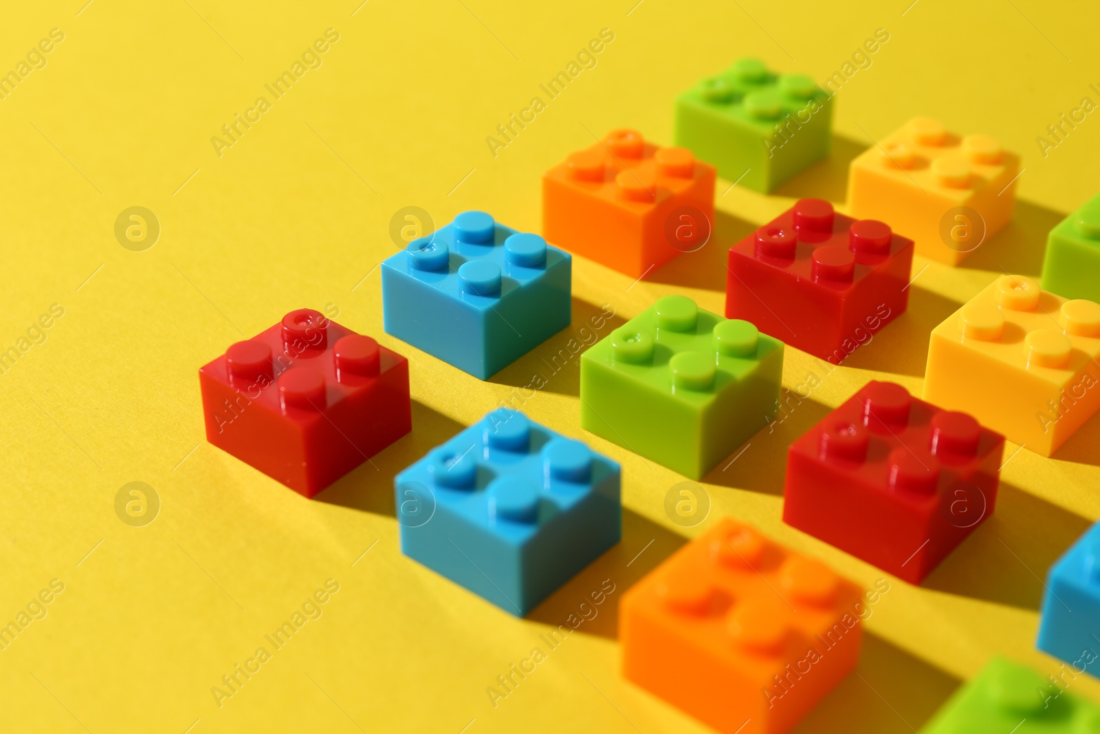 Photo of Construction toy. Colorful building bricks on yellow background, closeup