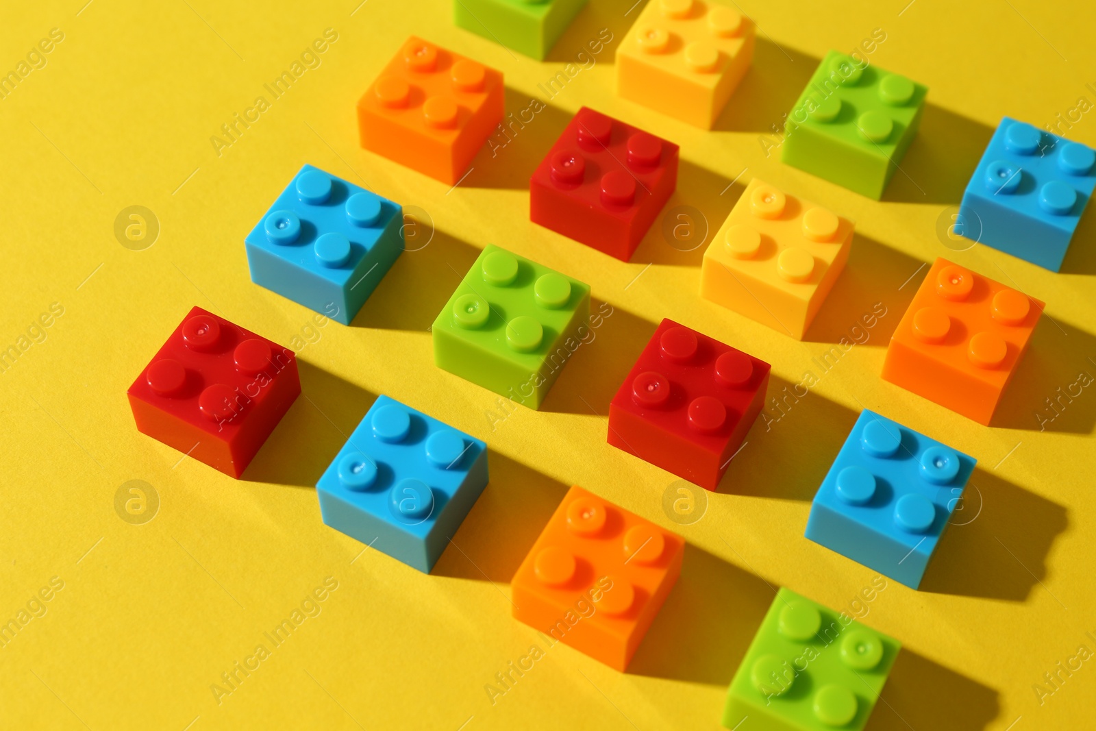 Photo of Construction toy. Colorful building bricks on yellow background, closeup