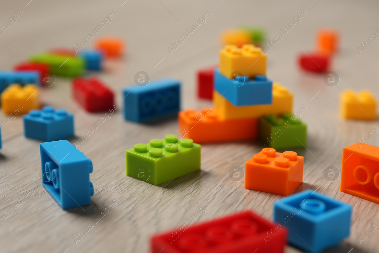 Photo of Construction toy. Colorful building bricks on wooden background, closeup