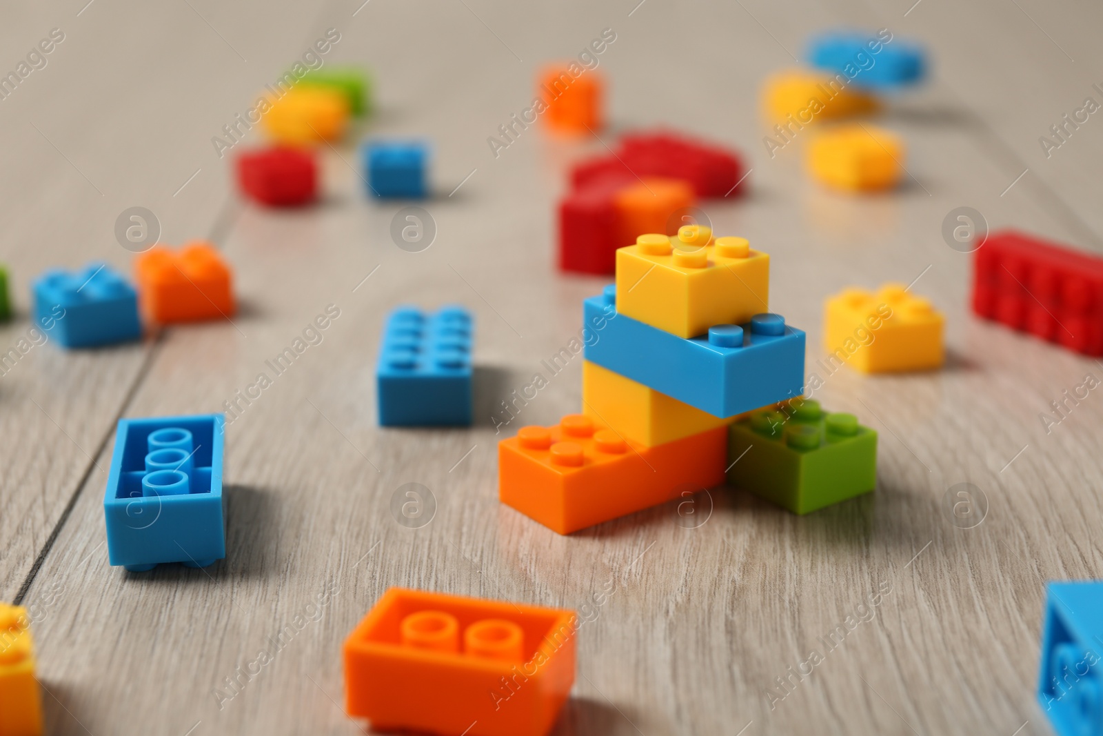 Photo of Construction toy. Colorful building bricks on wooden background, closeup