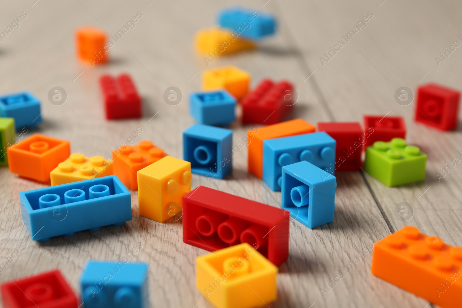 Photo of Construction toy. Colorful building bricks on wooden background, closeup