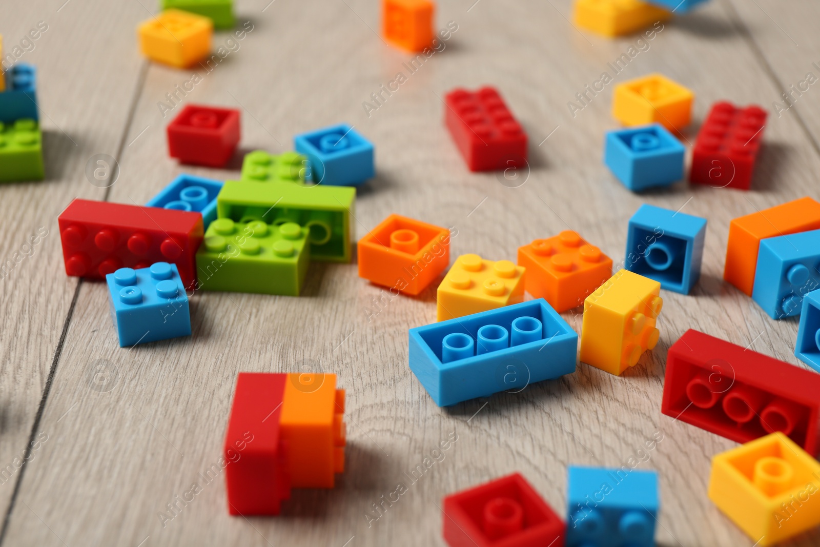 Photo of Construction toy. Colorful building bricks on wooden background, closeup