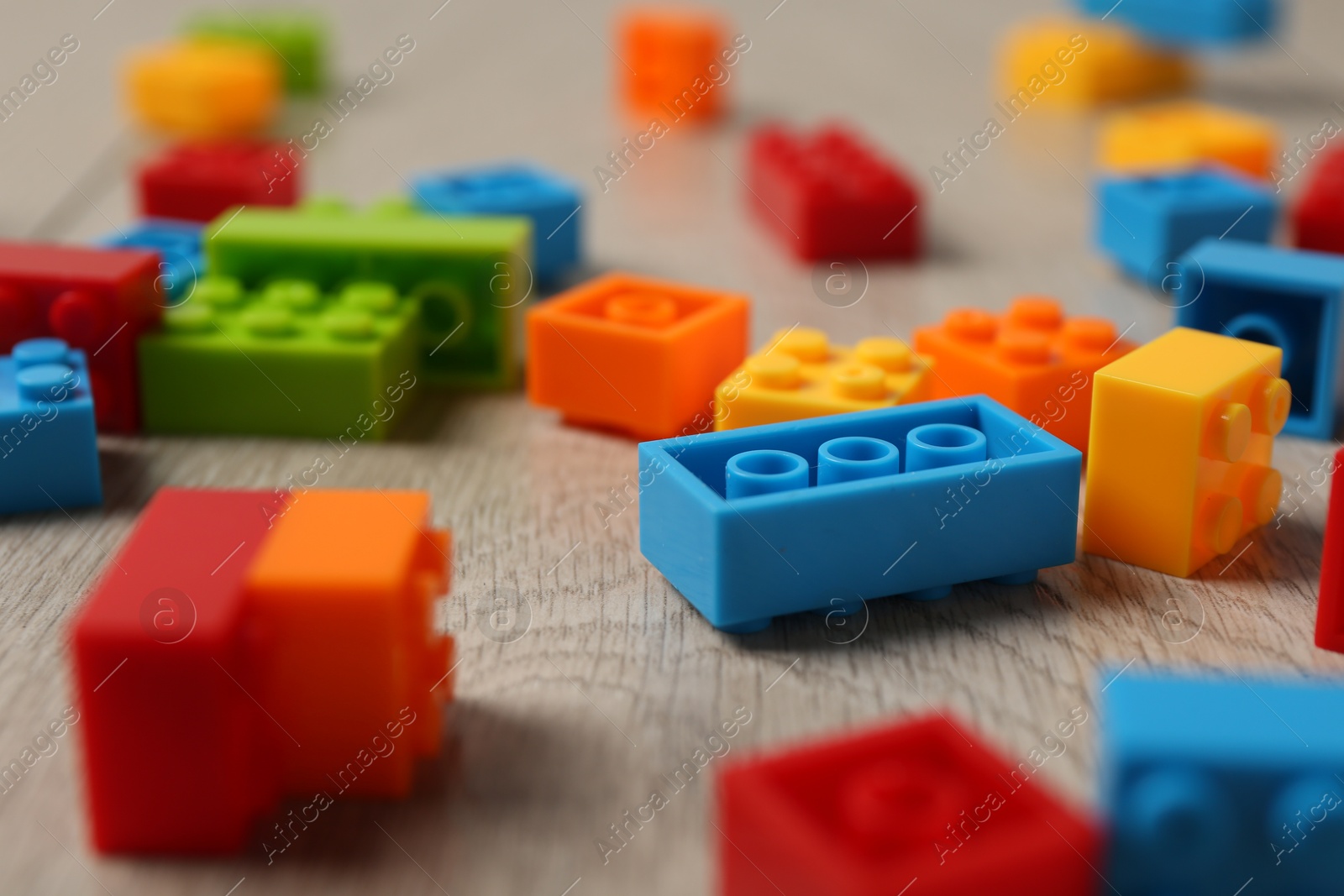 Photo of Construction toy. Colorful building bricks on wooden background, closeup