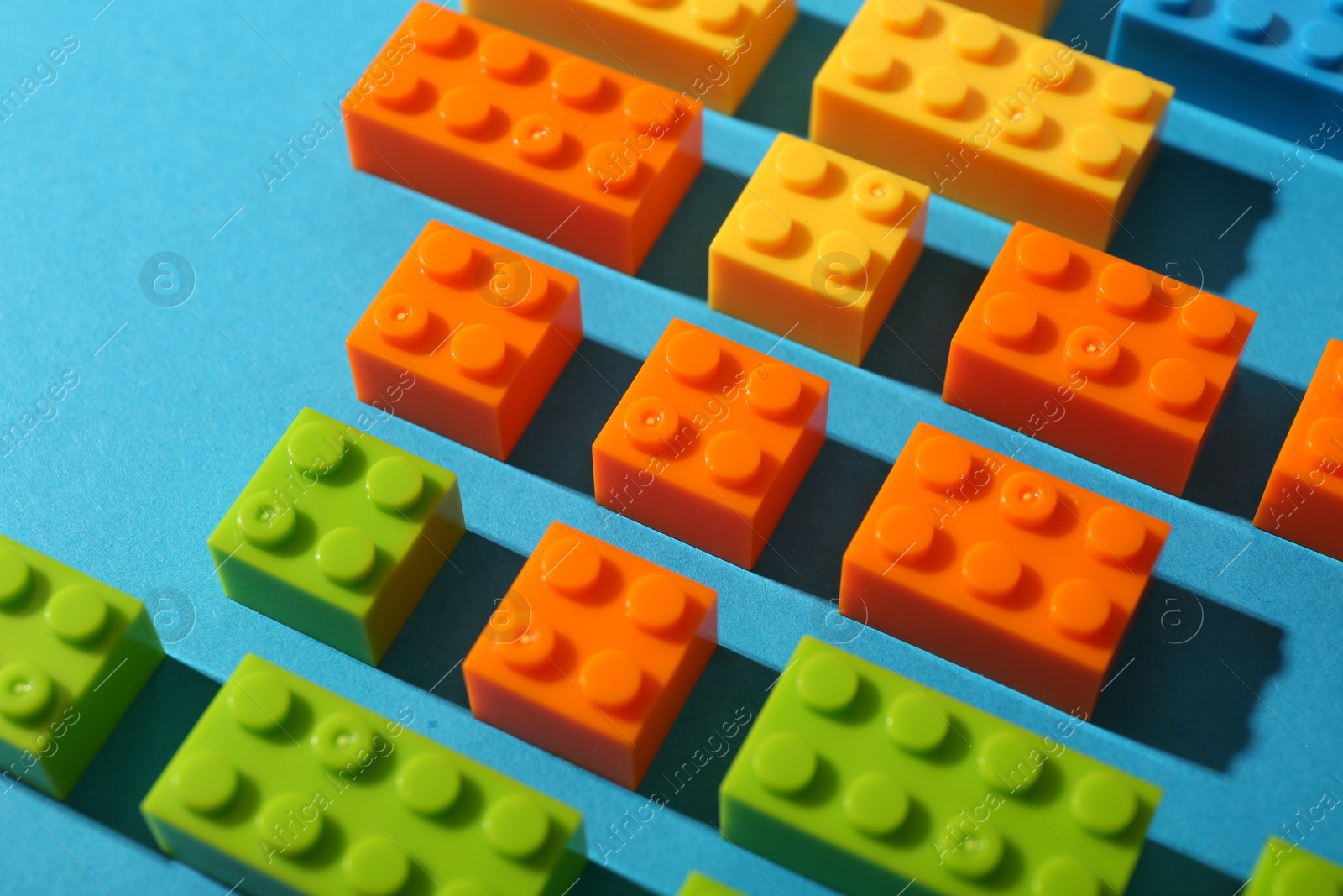 Photo of Construction toy. Colorful building bricks on light blue background, closeup