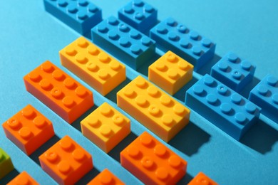 Photo of Construction toy. Colorful building bricks on light blue background, closeup