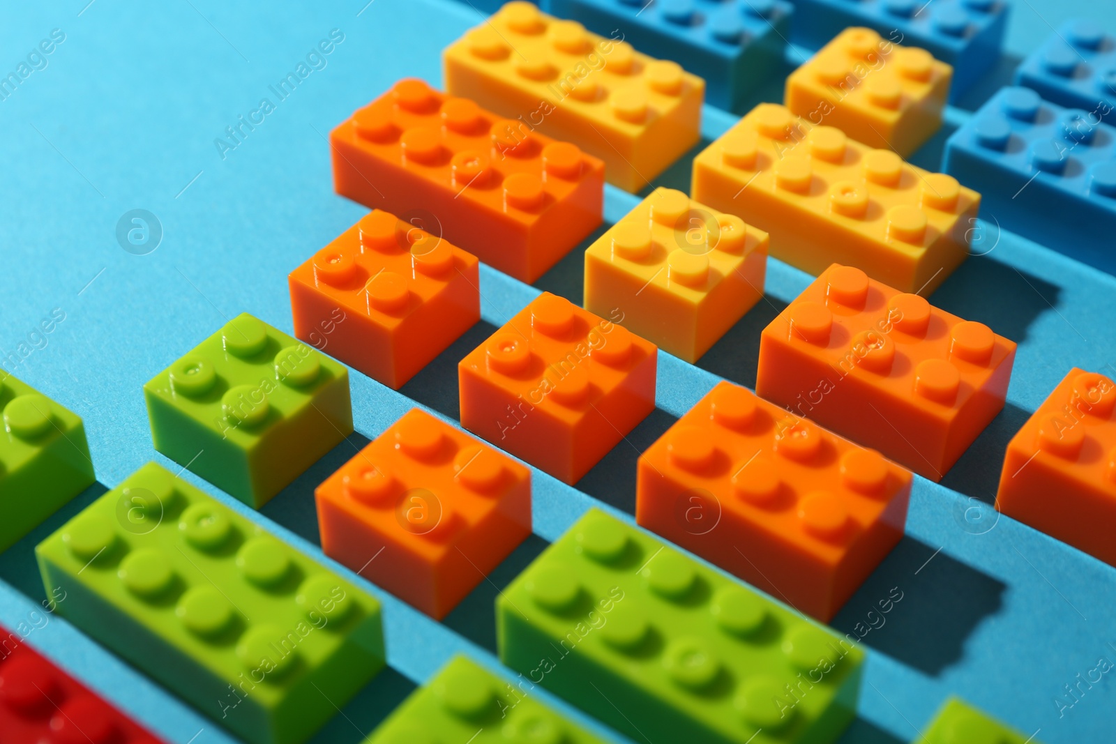 Photo of Construction toy. Colorful building bricks on light blue background, closeup