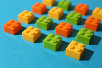 Photo of Construction toy. Colorful building bricks on light blue background, closeup