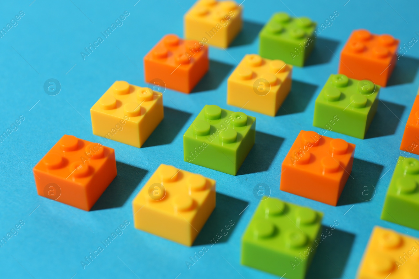 Photo of Construction toy. Colorful building bricks on light blue background, closeup