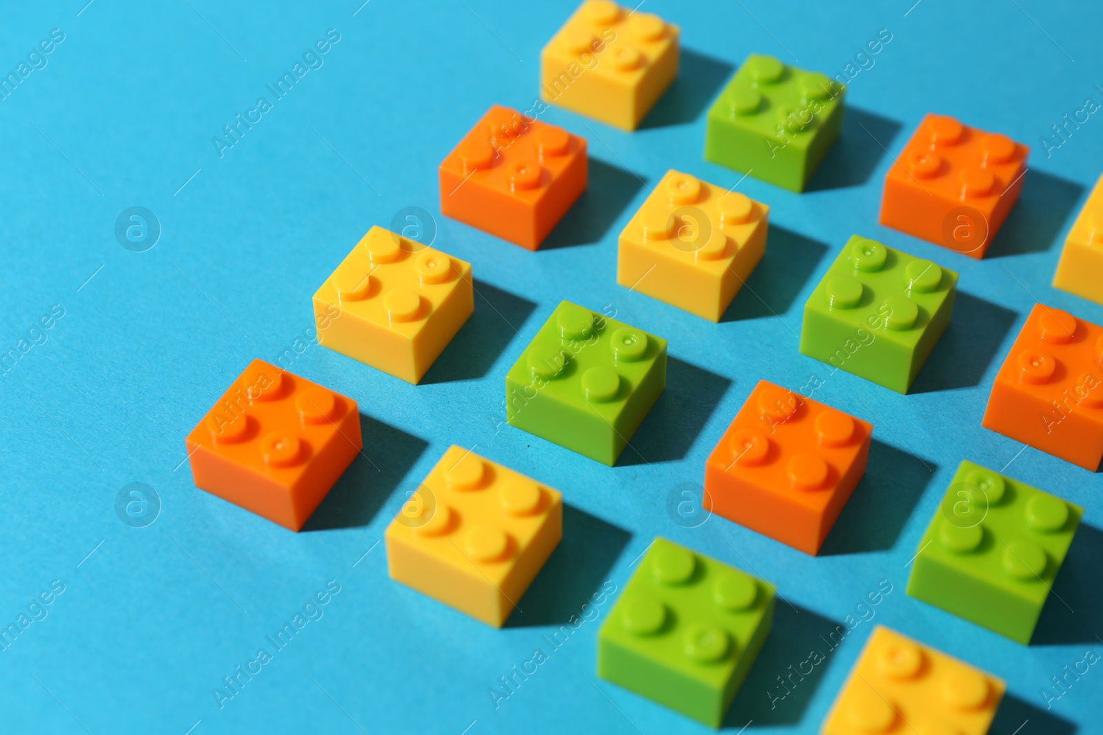 Photo of Construction toy. Colorful building bricks on light blue background, closeup