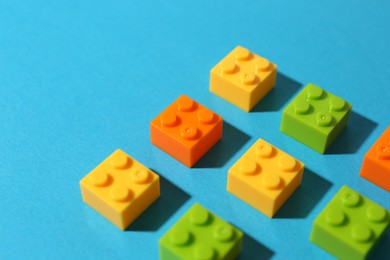 Photo of Construction toy. Colorful building bricks on light blue background, closeup. Space for text