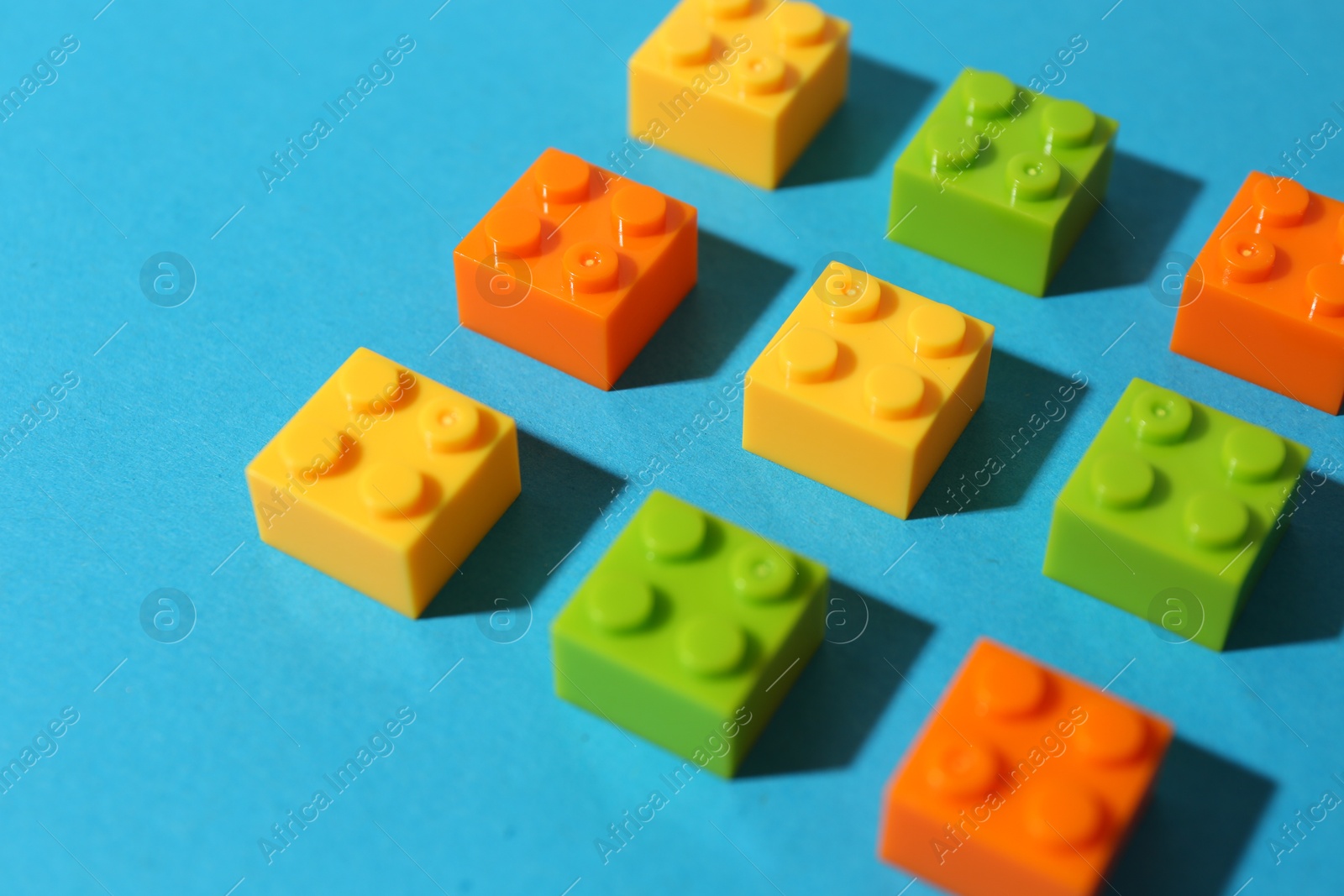 Photo of Construction toy. Colorful building bricks on light blue background, closeup