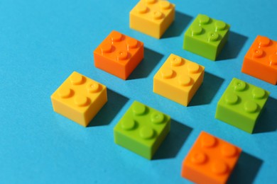 Photo of Construction toy. Colorful building bricks on light blue background, closeup