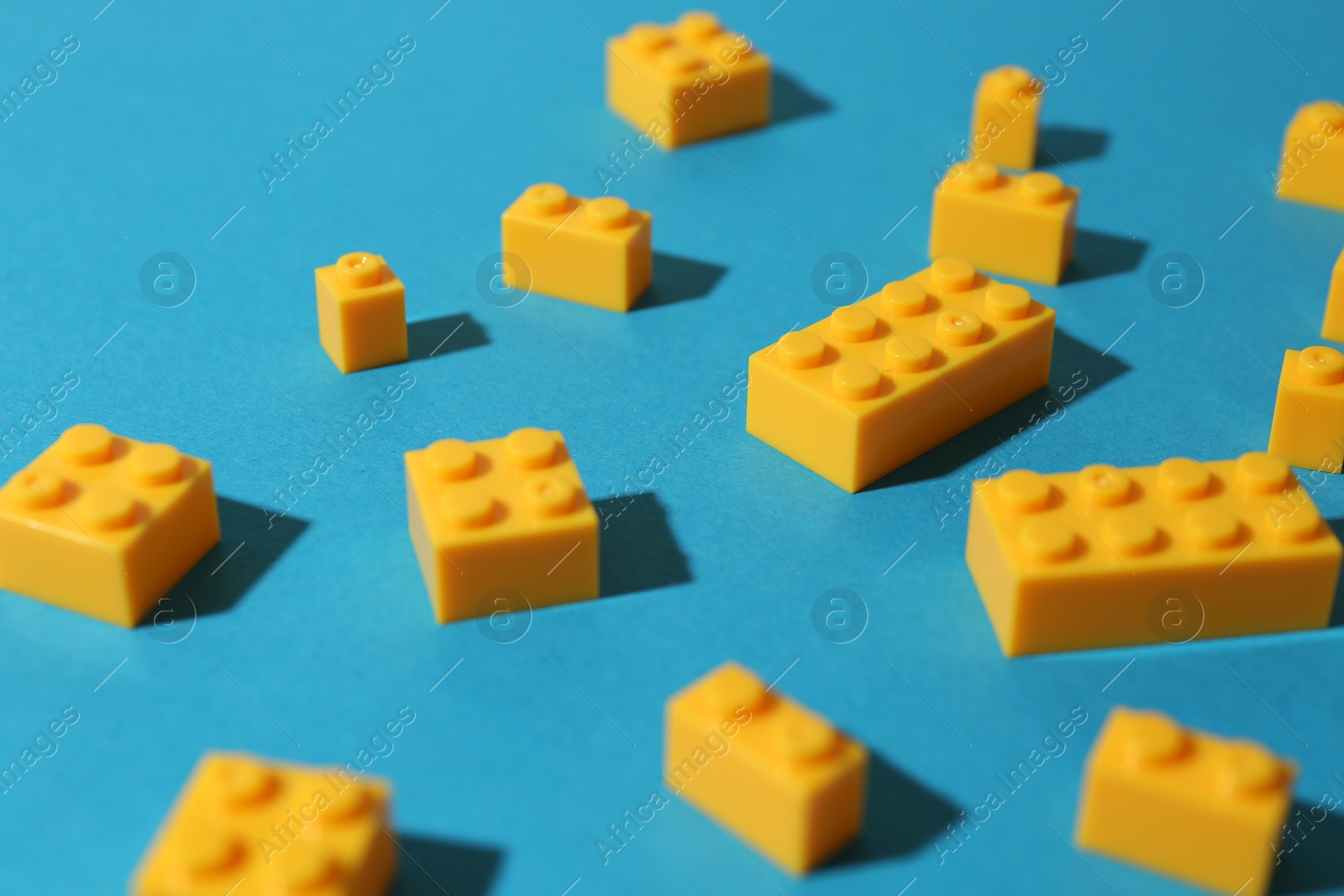 Photo of Construction toy. Colorful building bricks on light blue background, closeup