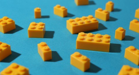 Photo of Construction toy. Colorful building bricks on light blue background, closeup