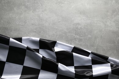 Photo of Checkered flag on grey table, top view. Space for text