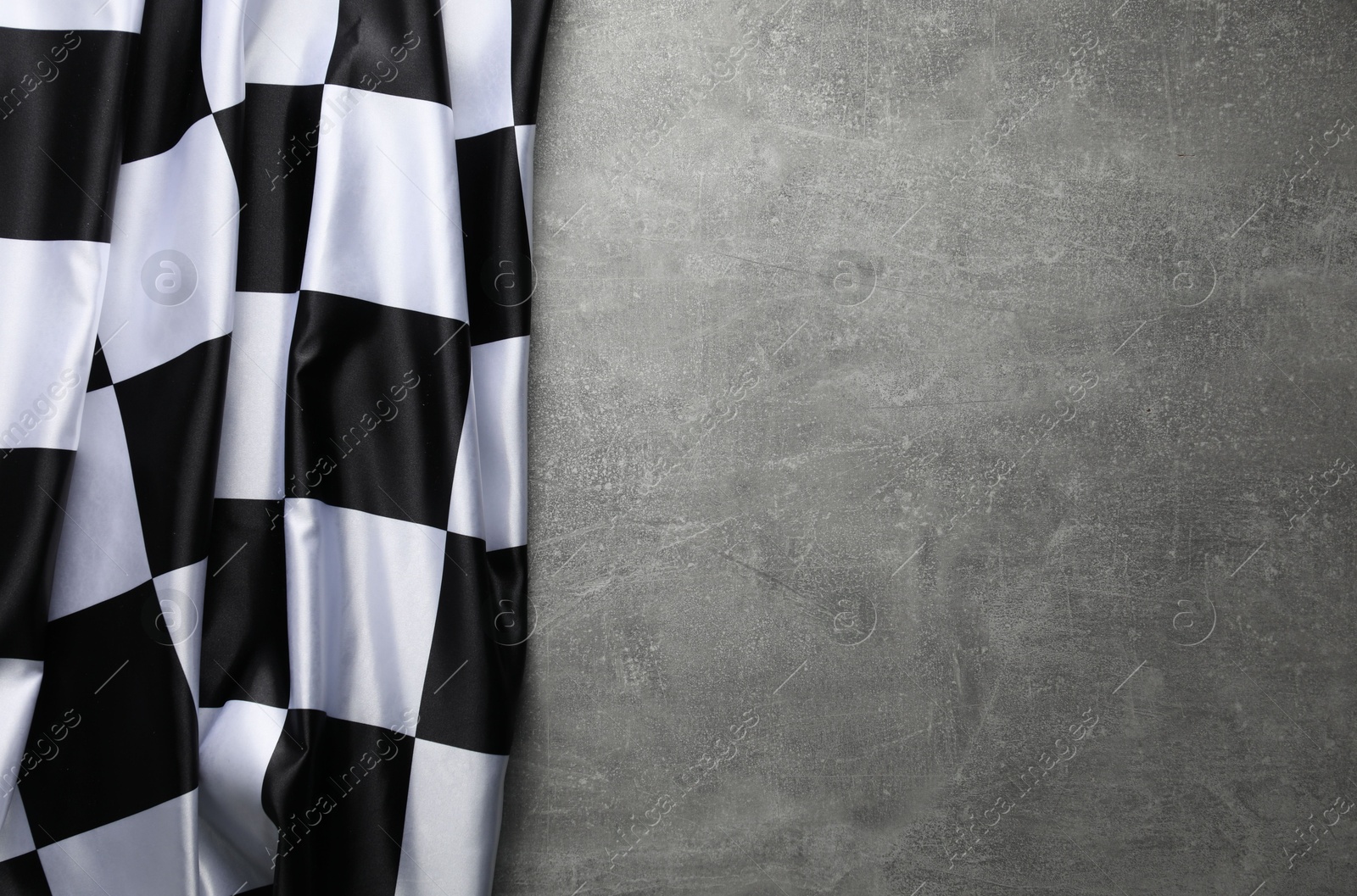 Photo of Checkered flag on grey table, top view. Space for text