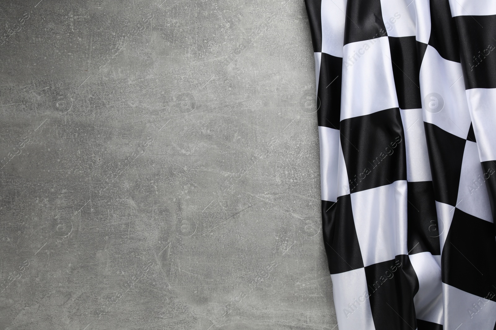 Photo of Checkered flag on grey table, top view. Space for text