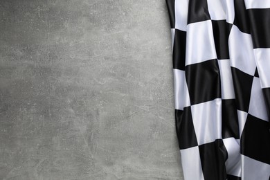 Photo of Checkered flag on grey table, top view. Space for text