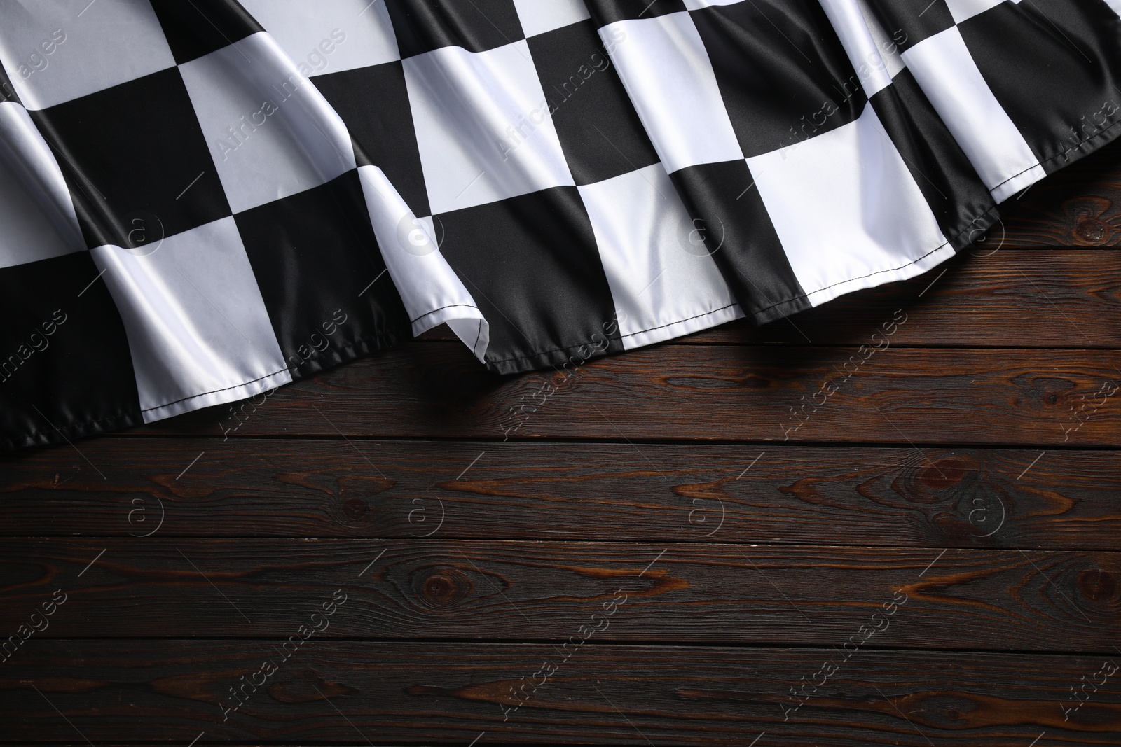 Photo of Checkered flag on wooden table, top view. Space for text