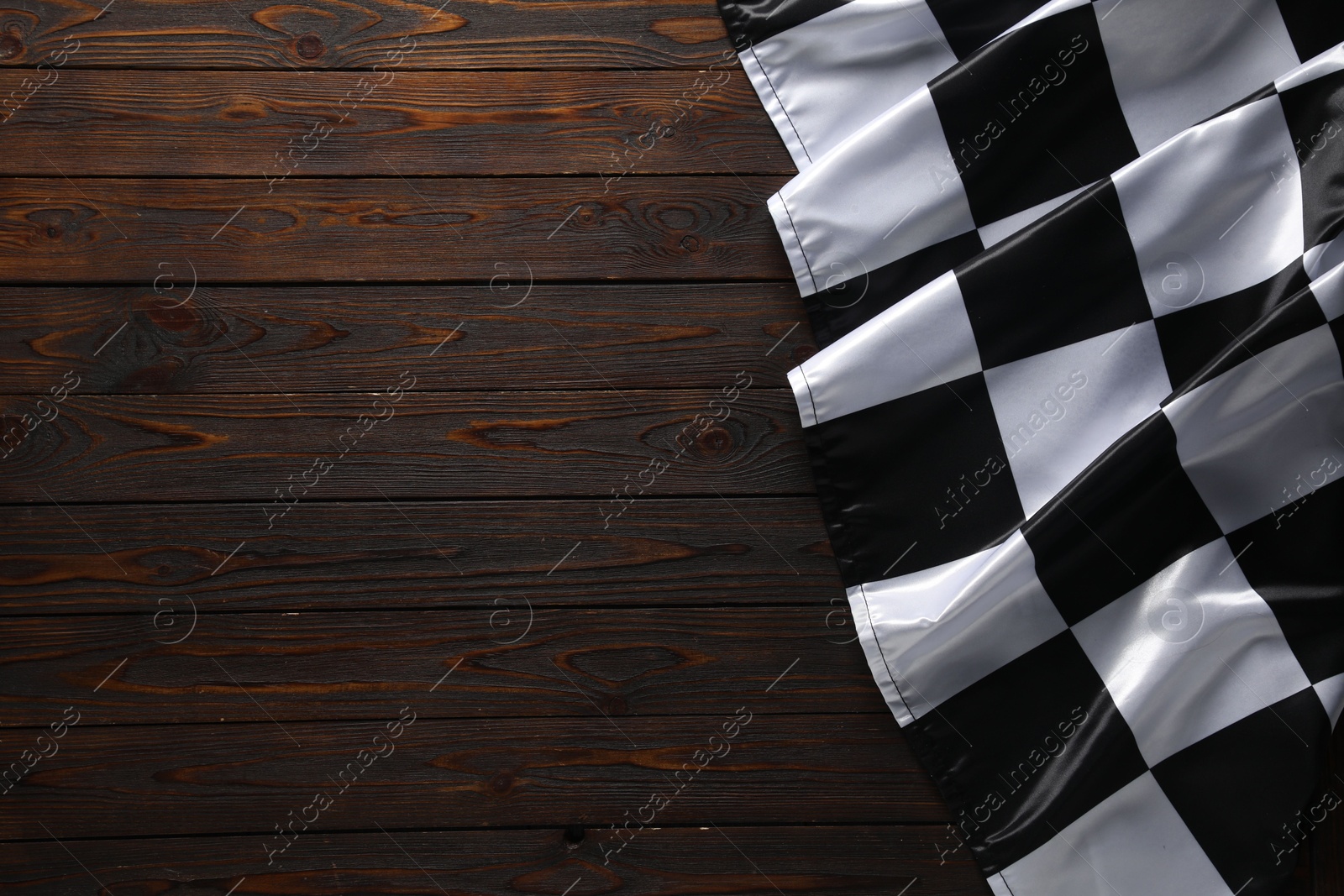 Photo of Checkered flag on wooden table, top view. Space for text