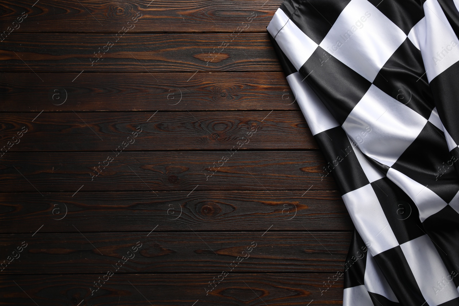 Photo of Checkered flag on wooden table, top view. Space for text