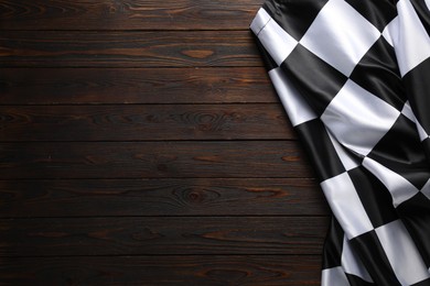 Photo of Checkered flag on wooden table, top view. Space for text