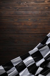 Photo of Checkered flag on wooden table, top view. Space for text